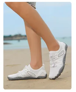 Detail view of white mesh water shoes worn on feet during outdoor beach activities.