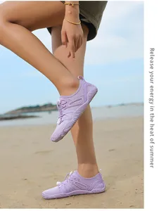 Close-up of purple outdoor water shoes worn by a model on a sandy beach