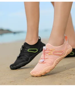 Close-up of peach-colored water shoes worn on a sandy beach for outdoor sports.