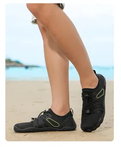 Black outdoor water shoes with neon green accents on a sandy beach background