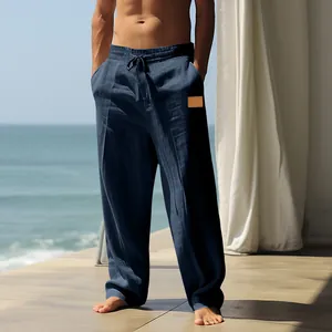Man wearing navy blue loose-fitting drawstring linen beach trousers on a sunny balcony