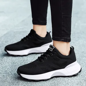 Atmungsaktive schwarze Mesh-Sneaker mit dicker weißer Sohle an einem Model im Freien