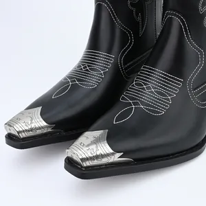 Detail van zwarte vintage cowboylaarzen met wit borduursel en zilverkleurige metalen neuskapjes
