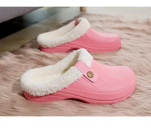 Detailed view of cozy pink winter clogs with plush white fleece lining on a rug.