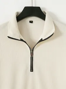 Gros plan d'un sweat-shirt pour homme en maille gaufrée crème avec col à demi-zip.