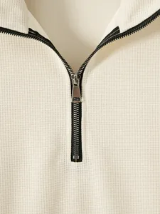 Vue détaillée de la fermeture éclair en métal noir et du tissu nid d'abeille du sweat-shirt
