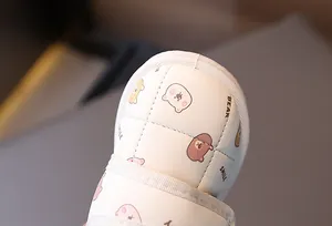 Macro detail of white quilted children's snow boot with cute cartoon bear pattern print.