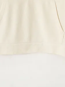 Vue détaillée montrant la texture gaufrée et l'ourlet du sweat à capuche crème.