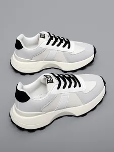 Vista dettagliata di sneaker bianche e grigie con spessa suola crema e lacci neri a contrasto