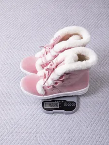 Warm pink fur-lined lace-up snow boots for women displayed on a digital weight scale