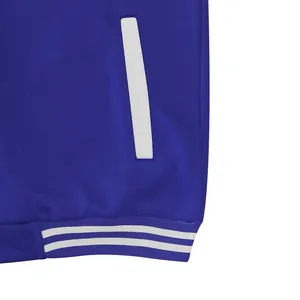 Detail van blauw varsity jack met witte paspelzak en gestreepte geribbelde boord.
