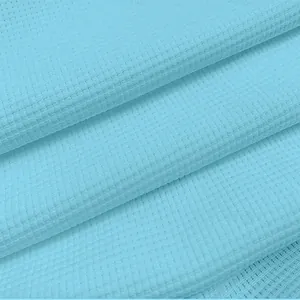 Macro view of light blue waffle knit fabric texture on a slim fit men's Polo shirt