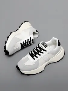 Vista dettagliata di sneakers chunky bianche e grigie con lacci neri e suole spesse.