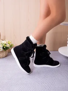 Detail of black fleece-lined snow boots with white soles and lace-up design
