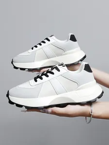 Dettaglio di eleganti sneakers chunky bianche con suole spesse antiscivolo outdoor.