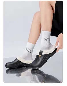 Close-up of black winter fleece-lined clogs with warm white lining on reflective surface