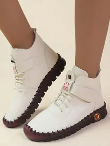 Detailopname van witte winterlaarzen met klittenbandsluiting en rode golfzool