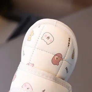 Close-up of children's white winter snow boots featuring cute cartoon bear patterns