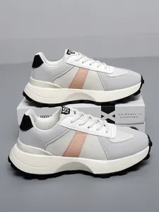 Primo piano di sneakers in pelle grigia e rosa impilate verticalmente su una scatola
