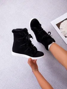 Close-up view of black faux fur snow boots featuring white flat soles and lace-up design