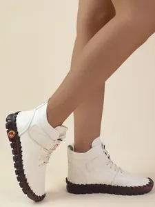 Detailweergave van witte winterlaarzen met klittenband gedragen door een model in studio