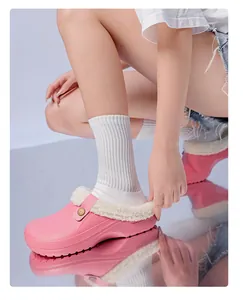 Pink winter clogs with warm white fleece lining, shown being worn by a model on reflection.