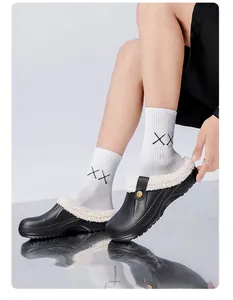 Nahaufnahme schwarzer gefütterter Winter-Clogs mit weißem Pelzbesatz und gemusterten Socken