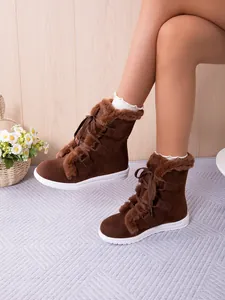 Detailed view of warm brown snow boots with plush faux fur lining and white sole.