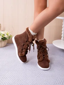 Close-up detail of brown plush winter snow boots with lace-up design and faux fur trim