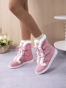 Detailed view of pink lace-up snow boots with white faux fur lining worn by a model