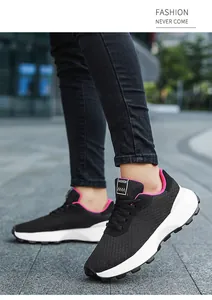 Side view of black breathable sneakers with pink trim on outdoor pavement