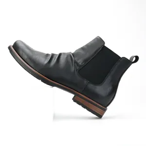 Side profile detail of men's black Chelsea boots with ruched leather and elastic goring