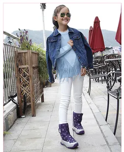 Full length photo of purple children's snowflake snow boots for winter worn by a young girl