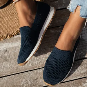 Detailansicht der atmungsaktiven dunkelblauen Flyknit-Slipper auf Holzgrund.