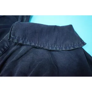 Close-up of dark navy washed fabric detail with distressed edges on jumpsuit