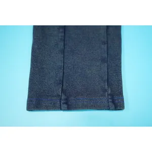Close-up macro view of the washed blue ribbed fabric and blue stitching on the jumpsuit hem