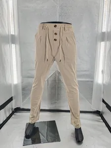 Dettaglio dei pantaloni in lino beige da uomo con bottoni decorativi e coulisse in vita.