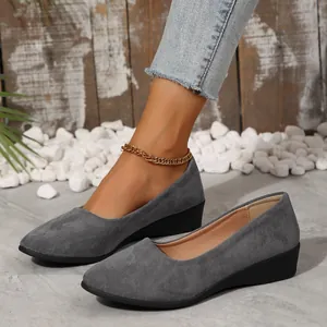 Vista detallada de elegantes zapatos de cuña en ante gris con un diseño de punta fina