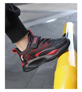 Nahaufnahme der schwarzen Leder-Sneaker für Kinder mit roten Akzenten und Klettverschluss