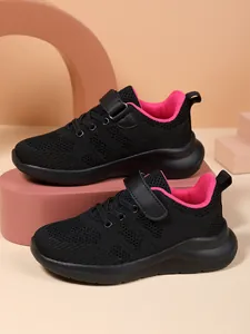 Detail van zwarte ademende mesh meisjessneakers met roze voering en klittenbandsluiting.