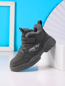 Primer plano de botas de invierno grises forradas para niños con suelas antideslizantes.