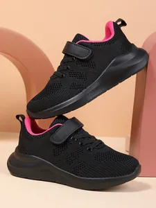 Zijaanzicht van ademende meisjessneakers in zwart met een felroze binnenvoering van mesh