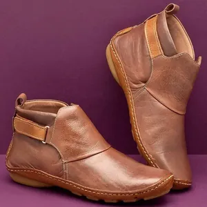 Bottines vintage en cuir souple marron avec coutures détaillées sur fond violet pour femmes chic.