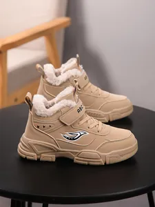 Primer plano de botas de invierno para niños con forro grueso de pelo sintético en color beige