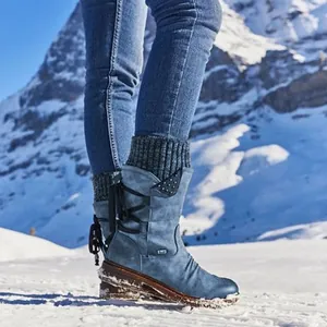 Vista lateral detallada de botas de nieve azules de media caña con puños de punto en la nieve