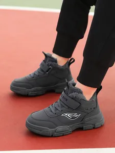 Primer plano de botas de invierno grises para niños con forro de piel sintética y velcro