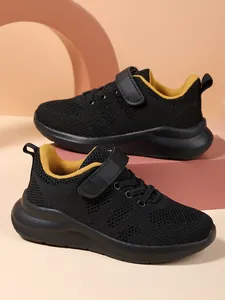 Close-up van ademende mesh kindersneakers in zwart met een gele binnenvoering.