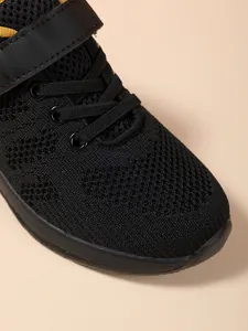 Close-up van zwarte ademende mesh sneakers voor meisjes met klittenbandsluiting.