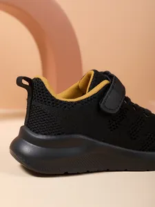 Detailopname van zwarte mesh kindersneakers met ademende stof en gele voering