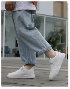 Zapatillas blancas de piel sintética para niños con vaqueros azules en un entorno exterior